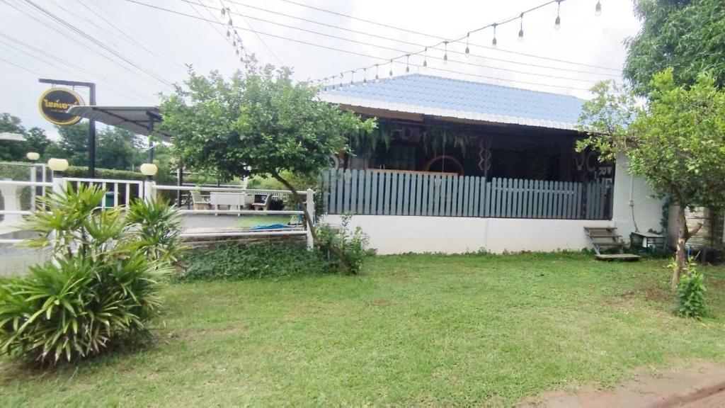 a white house with a fence and a yard at Hideout Homestay in Ban Rai Pa Yoe