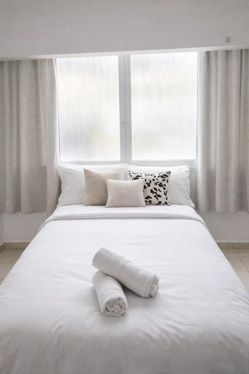 a white bed with white pillows and a window at R suite in Netanya
