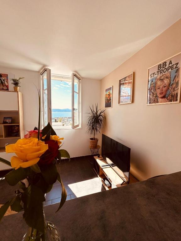 a living room with a vase of flowers and a television at La Madrague, Studio vue mer, Centre historique in Sainte-Maxime