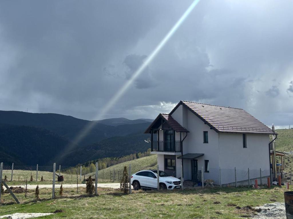 a white house with a car parked in front of it at Vila Narci Paltinis in Păltiniş