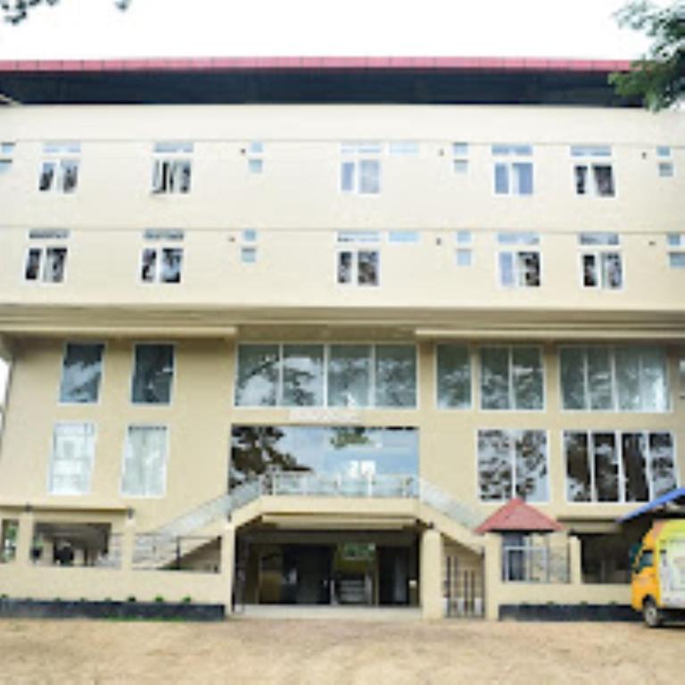 ein Gebäude, vor dem ein gelber Lieferwagen parkte in der Unterkunft Hotel Hempi in Diphu