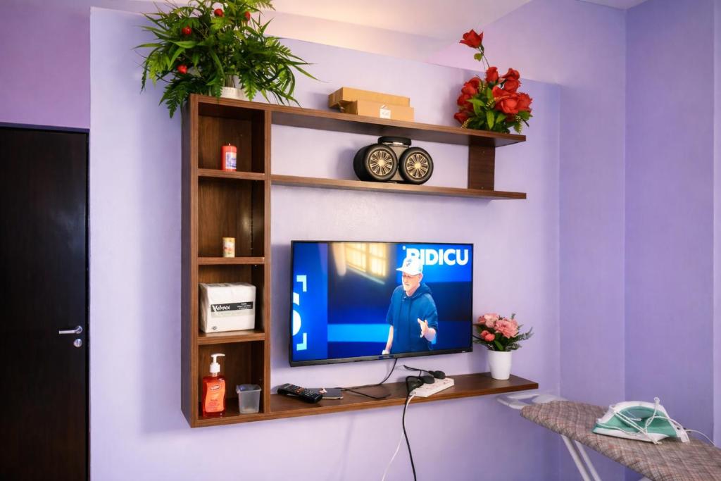 a living room with a television on a wall with shelves at Rose Gardens in Kitale