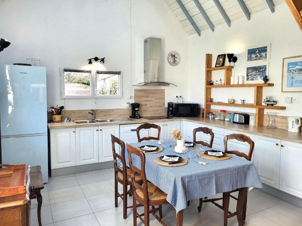 a kitchen with a table and chairs and a kitchen with white cabinets at Maison De Plage La Payade in Pirou