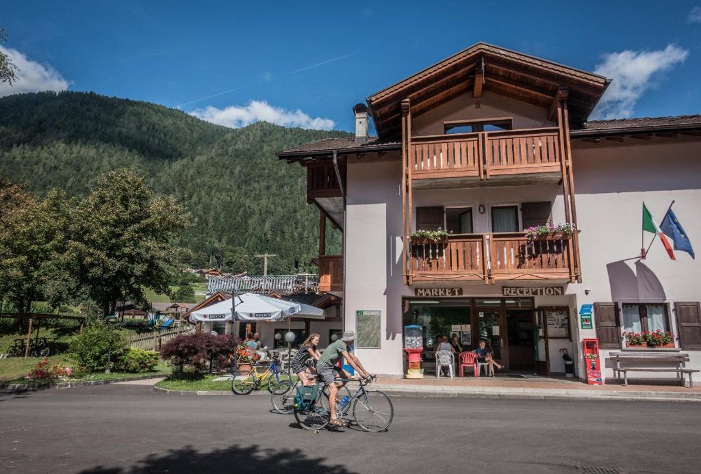 un par de personas en bicicleta delante de un edificio en Sarca Lodge Val Rendena, en Dare