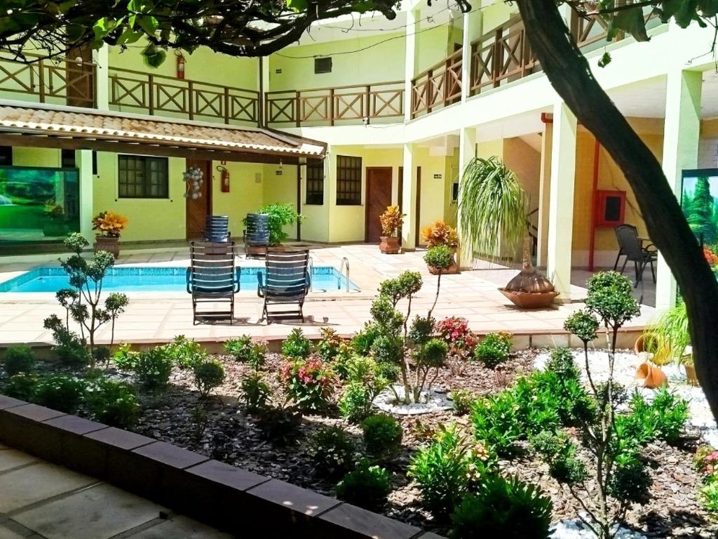 a garden in front of a building with a swimming pool at Condomínio Pousada Amarela 100 metros da Praia in Iguaba Grande