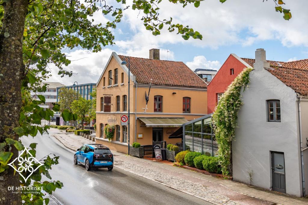 a blue car driving down a street with buildings at GamlaVærket Gjæstgiveri og Tracteringssted in Sandnes