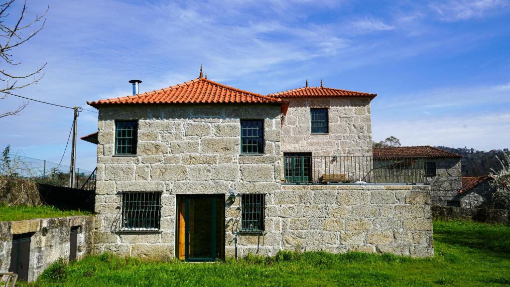 an old stone building with a red roof at Casa do Outeiro in Vila Meã