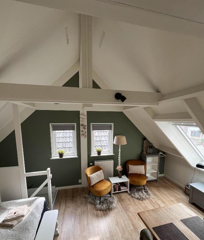 a room with a loft with a bed and two chairs at bed bij zee in Westkapelle