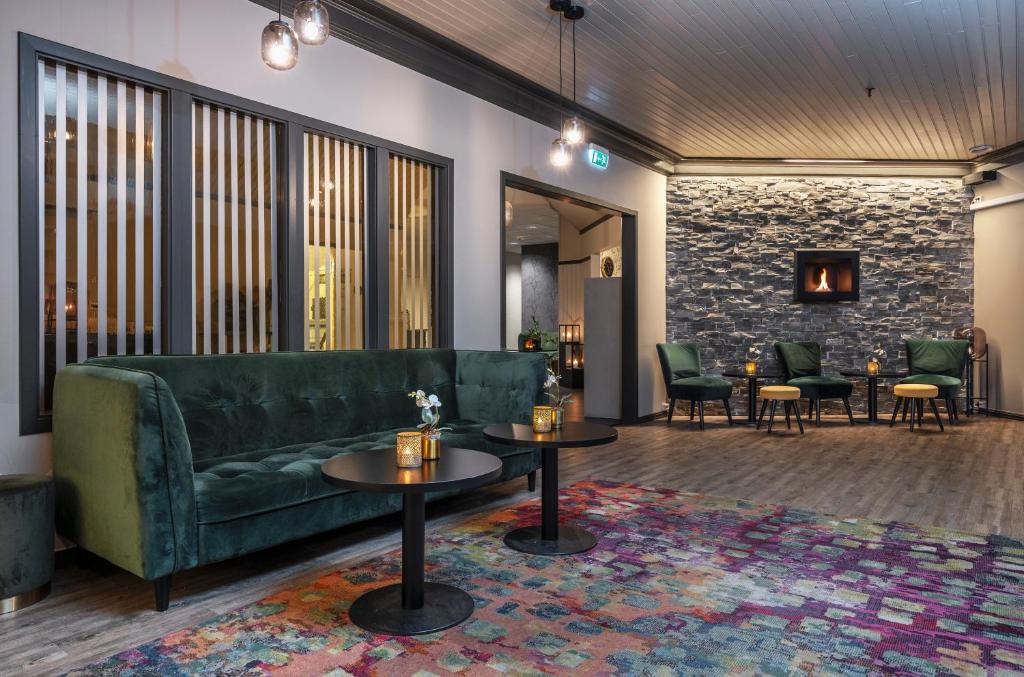 a living room with a green couch and tables at Thon Hotel Baronen in Ålesund