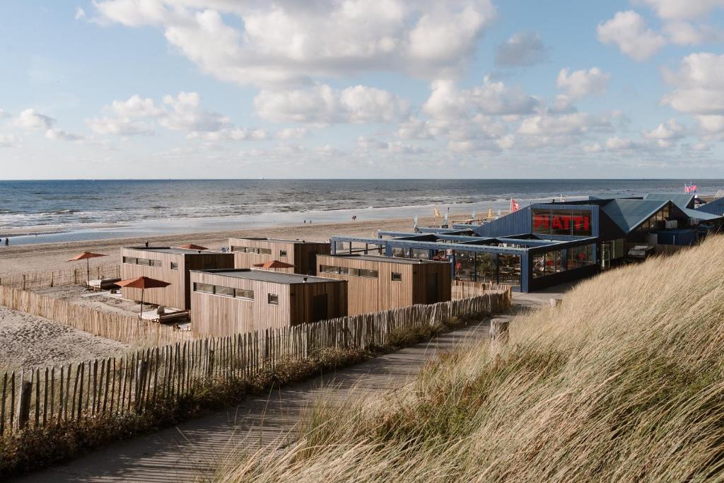 a beach with a building on the sand and the ocean at Piatti beach suites in Zandvoort
