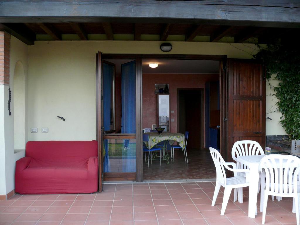 ポルペナッツェ・デル・ガルダにあるAppartamenti Polpenazzeの赤いソファ、パティオ(テーブル、椅子付)