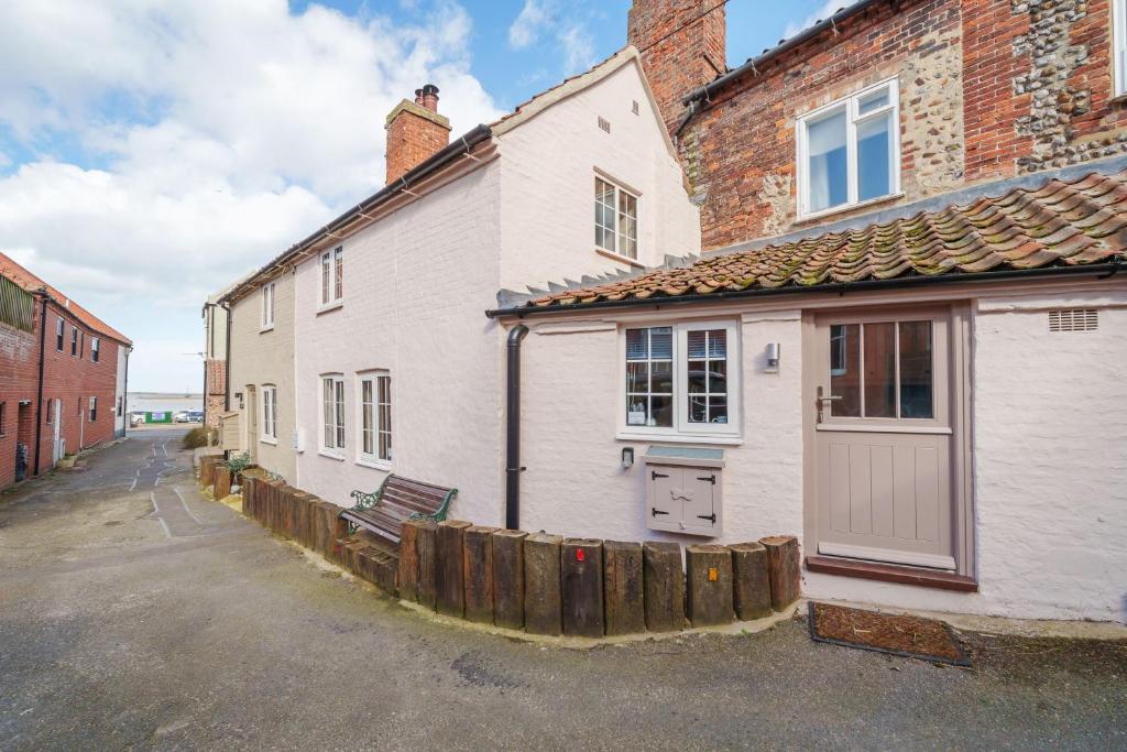 a white house with a wooden fence next to a building at Channel Cottage in Wells next the Sea