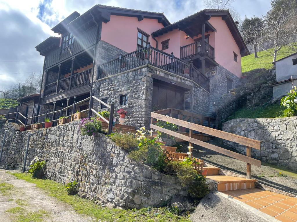 a house on a hill with a stone wall at Casa Rural La Xana in Piloña