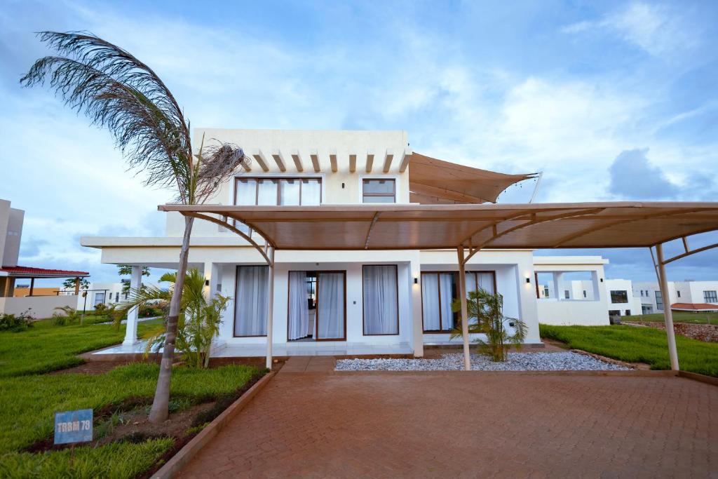 a white house with a palm tree in front of it at Spacious 3 bedroom ensuite villa Pazuri vipingo in Mombasa
