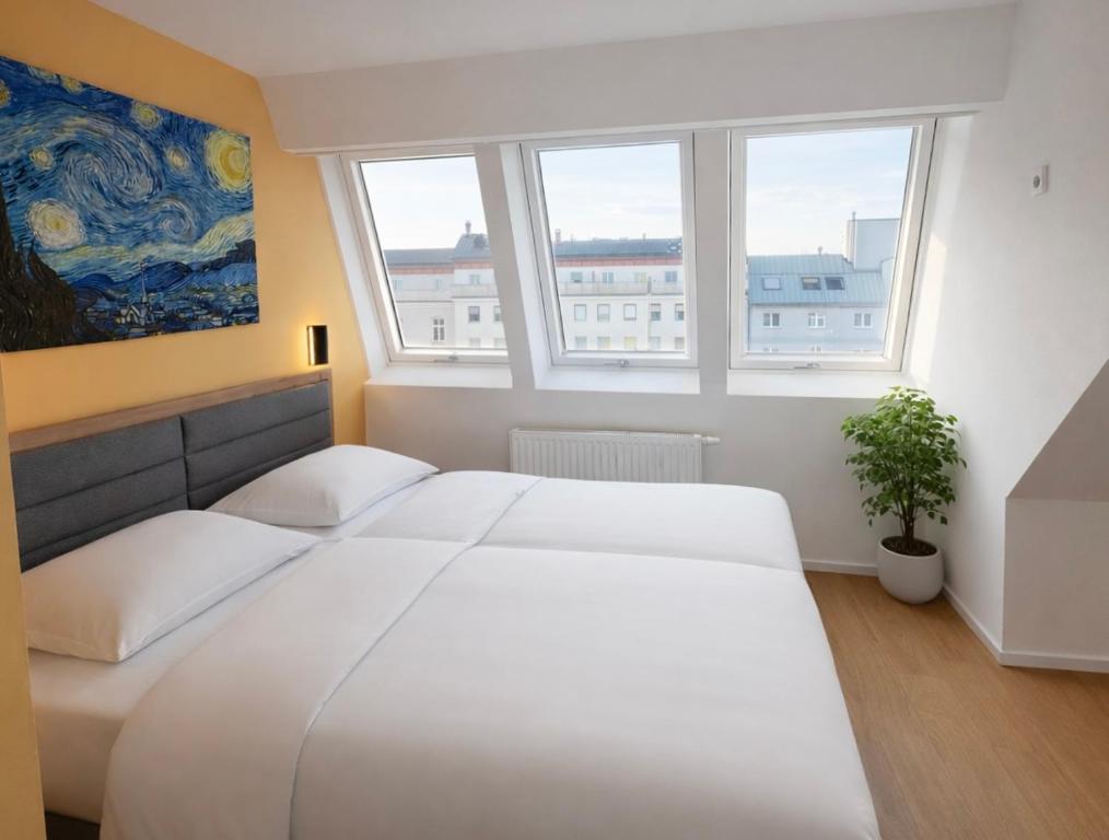 a bedroom with a large white bed and two windows at A&T Hotel & Hostel in Vienna