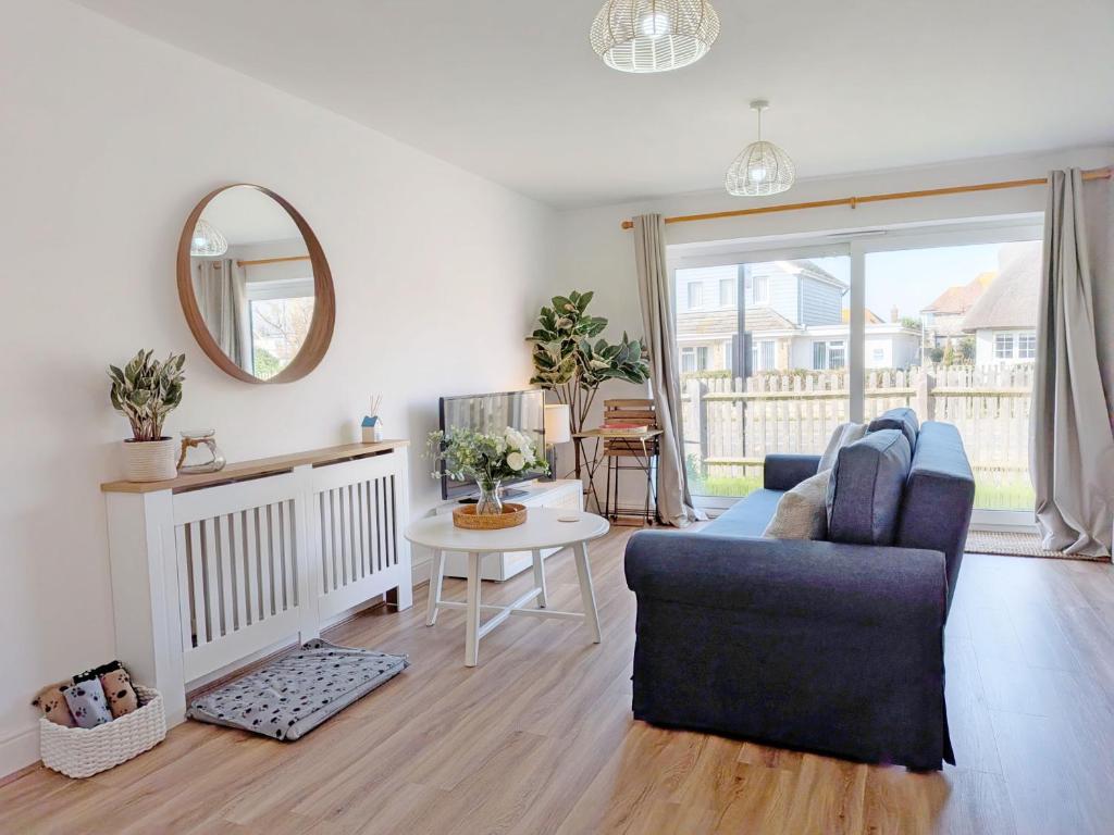 a living room with a couch and a table and a mirror at The Beach Flat - Selsey in Selsey