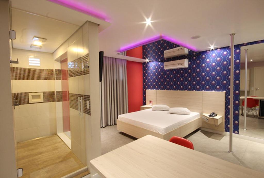 a bedroom with a bed and a glass shower at Flow Motel (Adult Only) in Valinhos