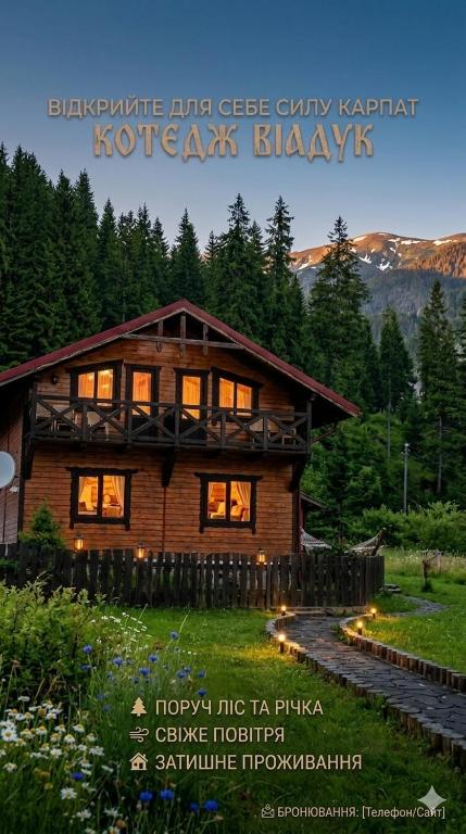 a large wooden house with lights in front of it at Котедж Віадук in Vorokhta