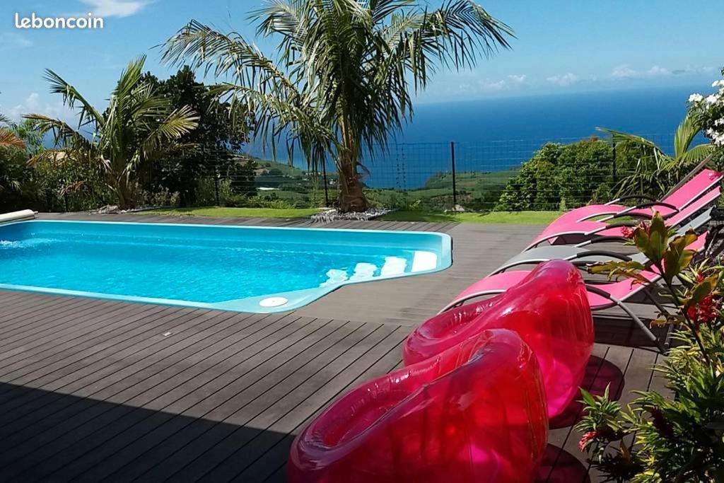 a swimming pool with lounge chairs next to the ocean at L' Amandava in Petite Île