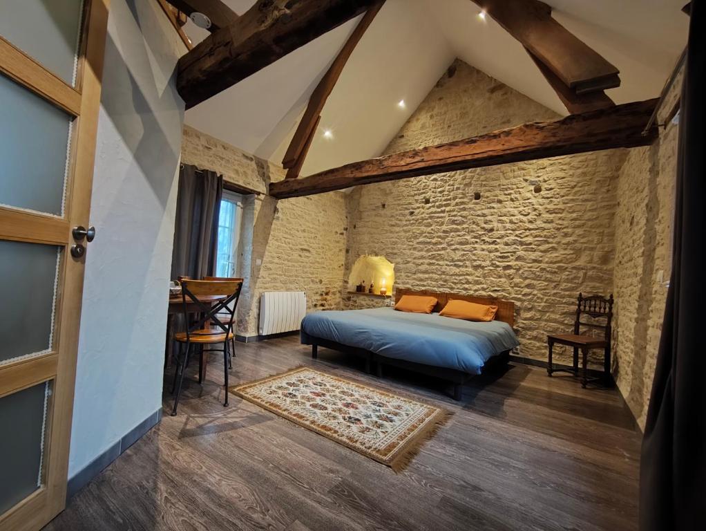 a bedroom with a bed and a brick wall at Omaha Secret Normandy Cottages in Saint-Laurent-sur-Mer