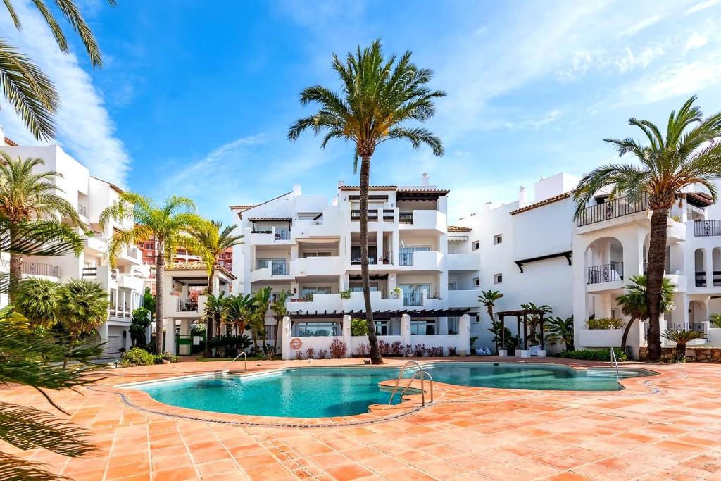 a resort with a swimming pool and palm trees at Fuente de la Duquesa in Manilva