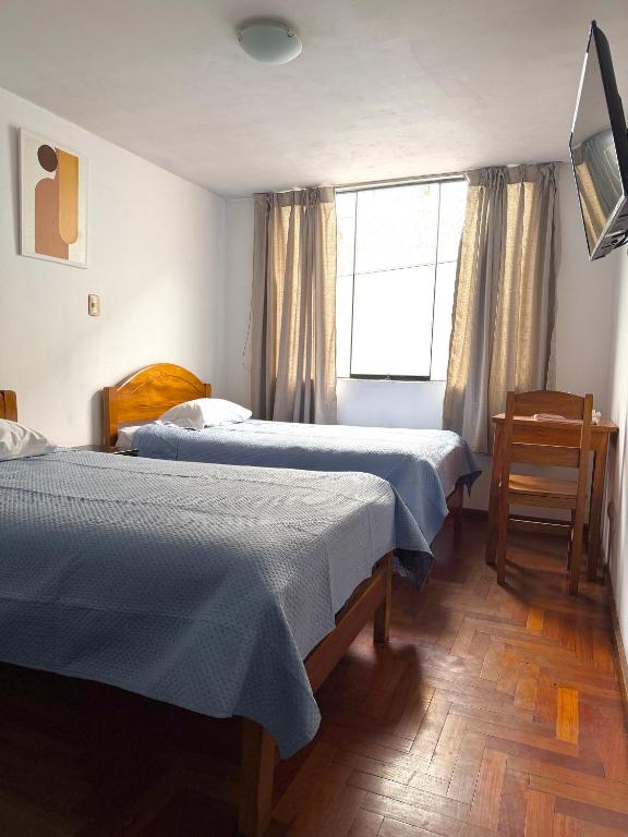 a hotel room with two beds and a window at Hostal Violeta in Arequipa