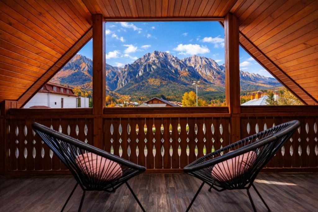 Zwei Stühle auf einer Veranda mit Blick auf die Berge in der Unterkunft The Bear Chalet with Private Hot Tub in Buşteni