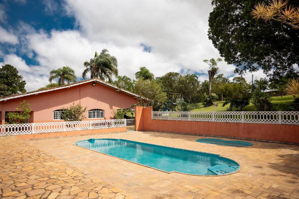 a house with a swimming pool in front of a fence at Véio Chico’s Ranch | Swimming Pool | Barbecue in Ibiúna