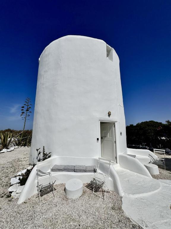 a white building with two chairs and a table at Windmill of Mykonos in Mikonos