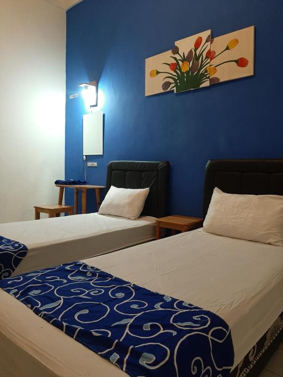 a hotel room with two beds and a blue wall at Edotel Tebe Syariah in Rampal