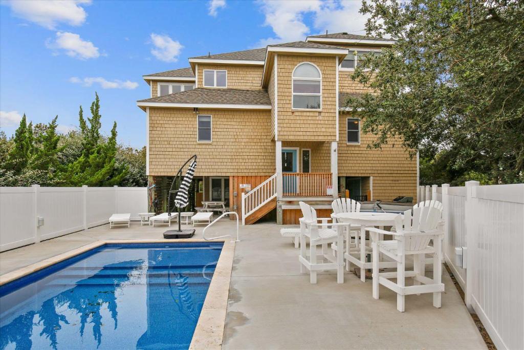 a house with a swimming pool and white fences at 1067 - Easy Street in Corolla