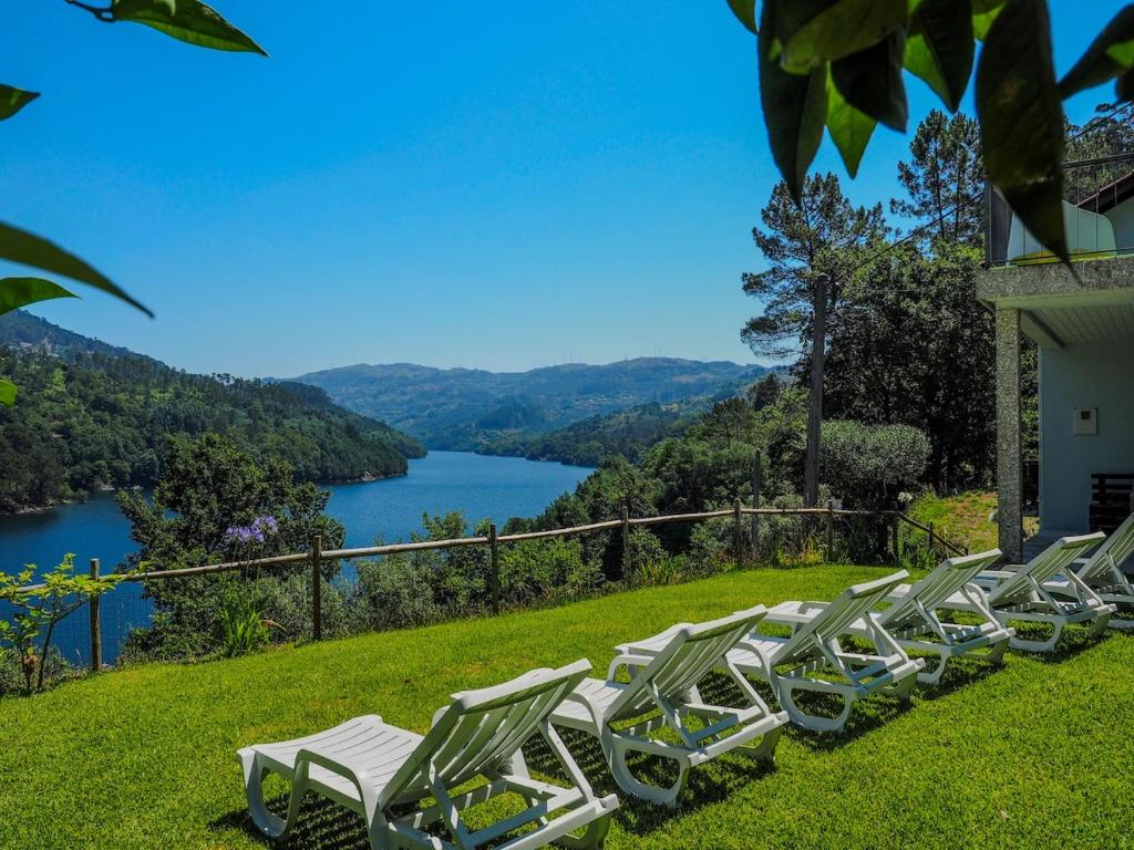 a row of white chairs on a lawn with a lake at Casa do Batoco in Vieira do Minho
