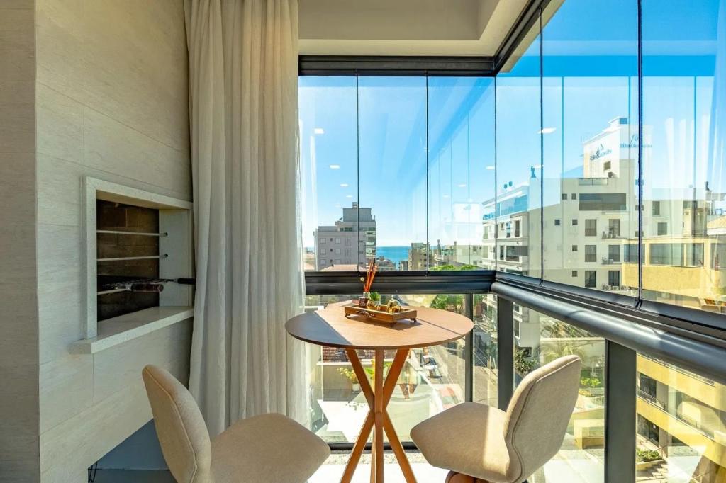 a room with a balcony with a table and chairs at Apartamento 2 suítes C/Piscina in Bombinhas