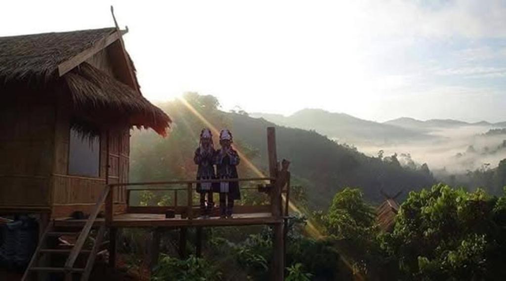 two people standing on a balcony of a house at Akha Hill House in Ban Doi Hang