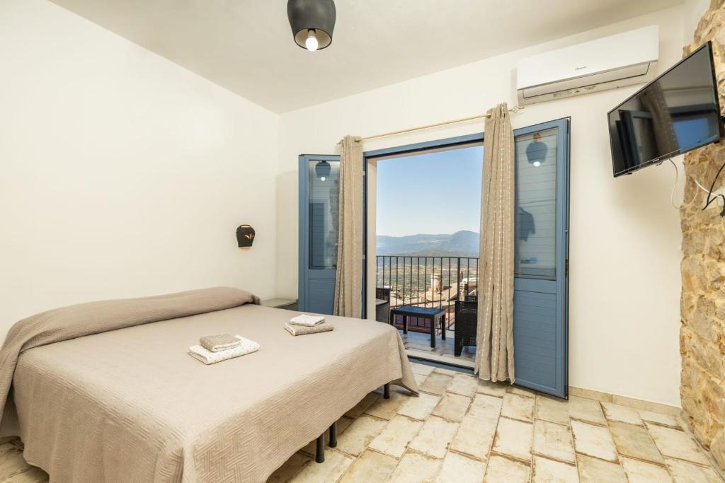 a bedroom with a bed and a tv and a balcony at B&B Golgo in Baunei