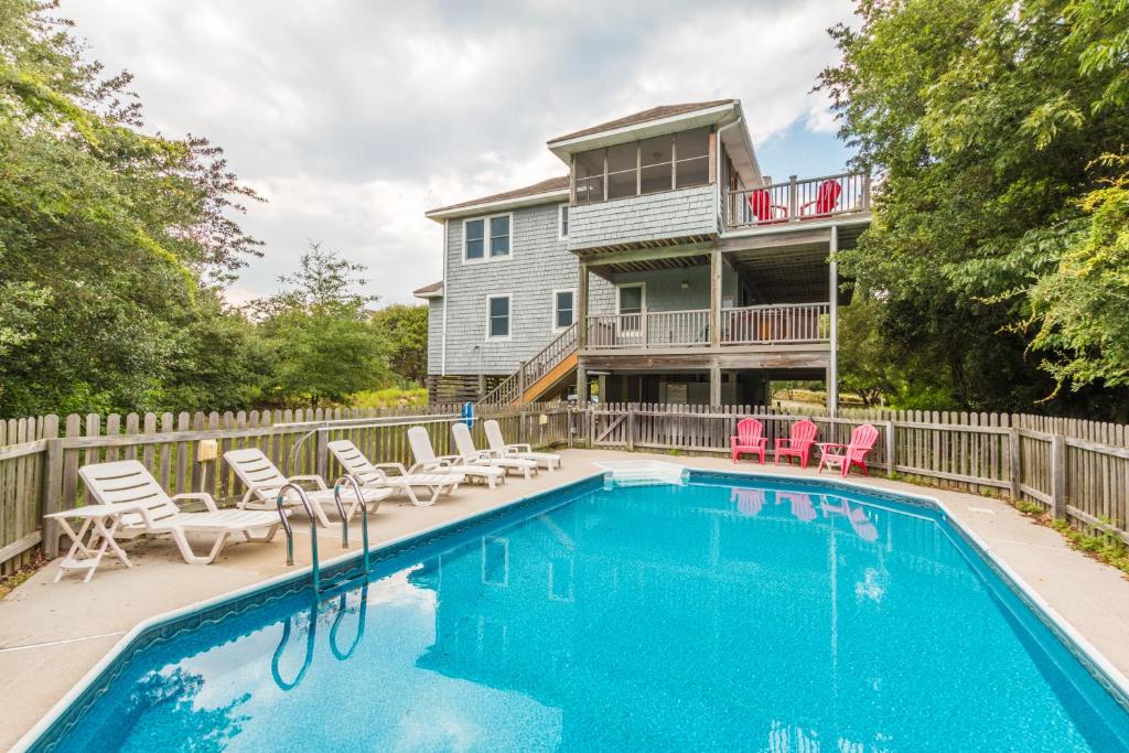 a swimming pool with chairs and a house at 3944 - Carolina Escape in Duck