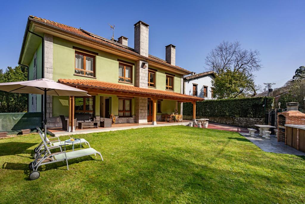 a house with a lawn and an umbrella in the yard at Apartamentos Rurales & Spa Antilles Playa in Llanes