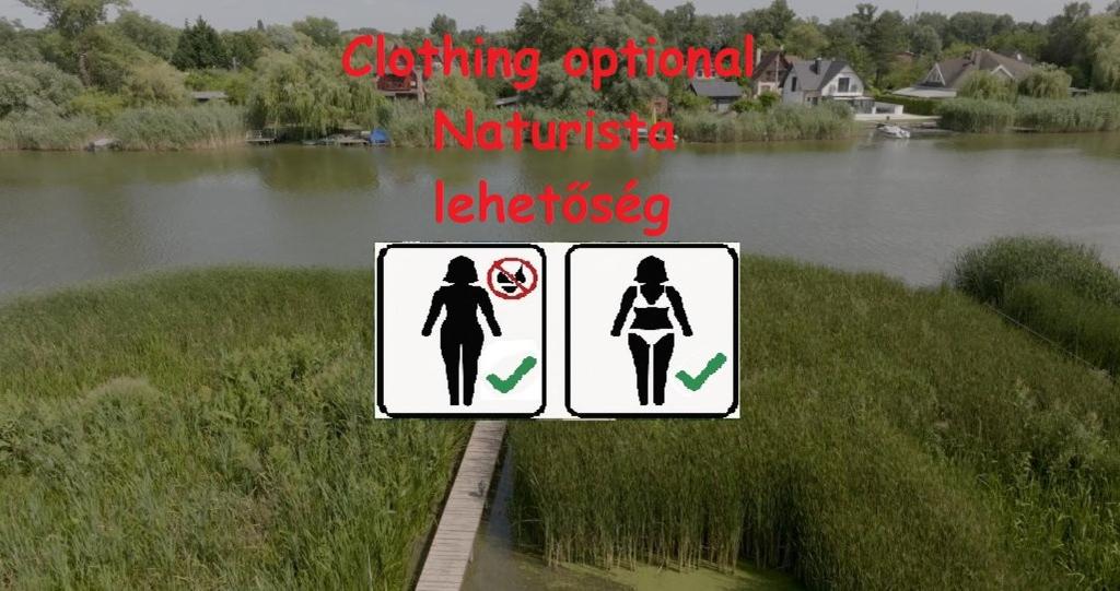 a sign with two women on a bridge next to a river at Miklós FKK Naturist in Szigetszentmiklós
