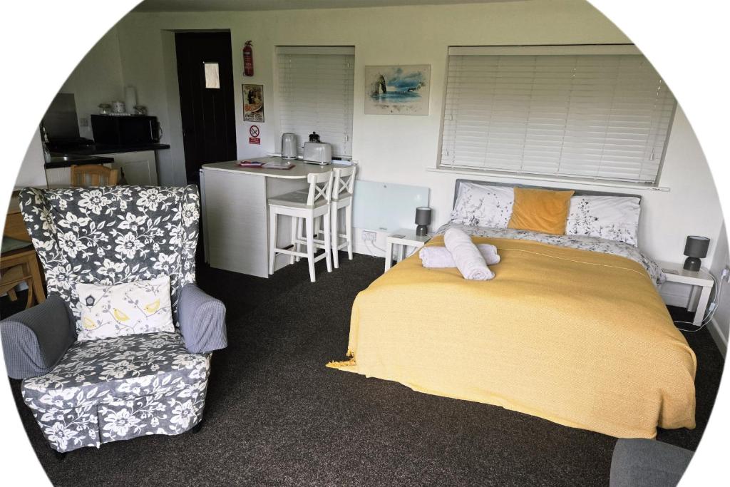 a bedroom with a bed and a chair and a table at The Piggery - Corfe Mullen in Corfe Mullen