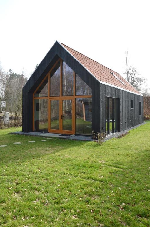 a black house with large glass windows in a field at Forest Villa De Bosburcht with Sauna | 6 persons in Gasselte