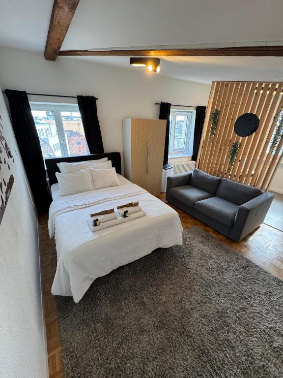 a bedroom with a large white bed and a couch at Cosy attic flat Lausanne center in Lausanne