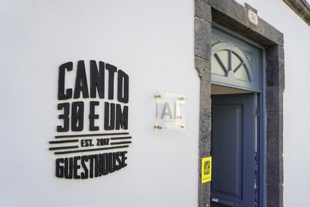 a sign on the side of a building with a door at Canto 30 e UM - HOST & CHILL in Ribeira Grande