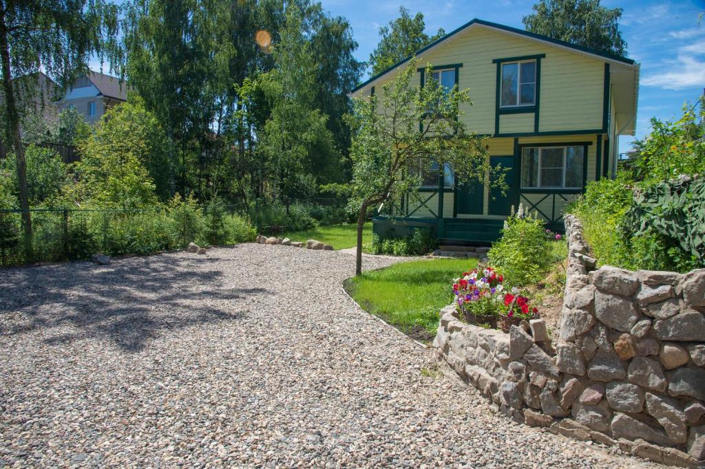 a house with a stone wall and a gravel driveway at Guest House U Pruda in Kostroma