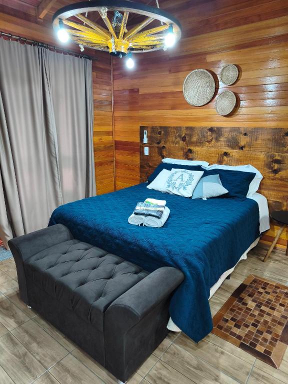 a bedroom with a bed with a blue blanket and a couch at Aconchego da Serra in São Joaquim