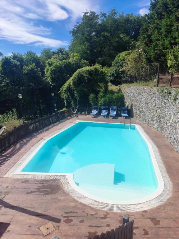 a large blue swimming pool with chairs around it at La Sorgente Apartment with private pool in Calice Ligure