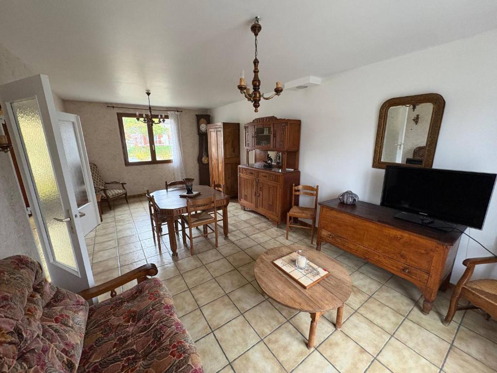 a living room with a couch and a tv and a table at Le Petit Puits de l Ange in Bonny-sur-Loire