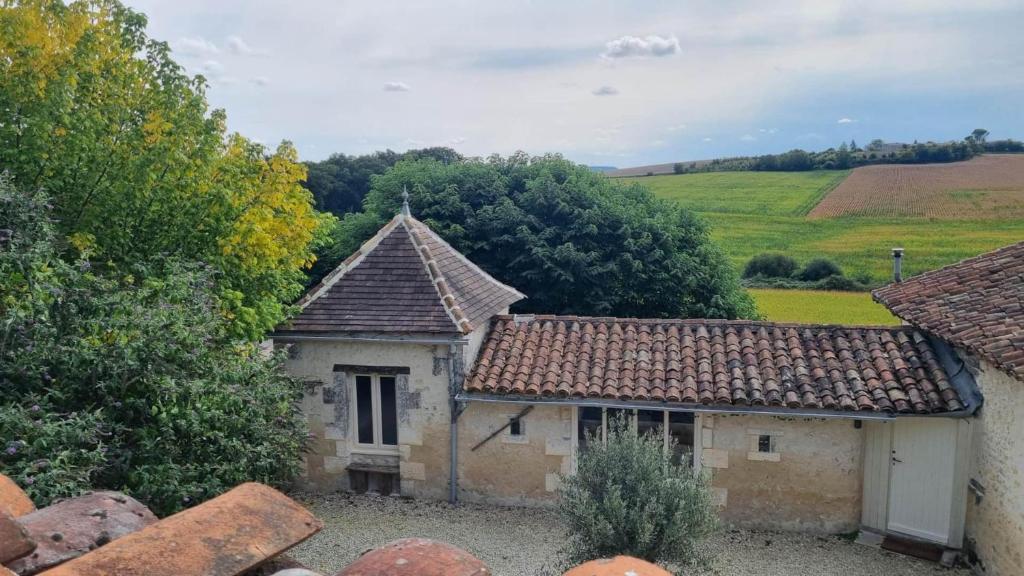 an old building with a roof on a field at La Chaumière in Salles-Lavalette