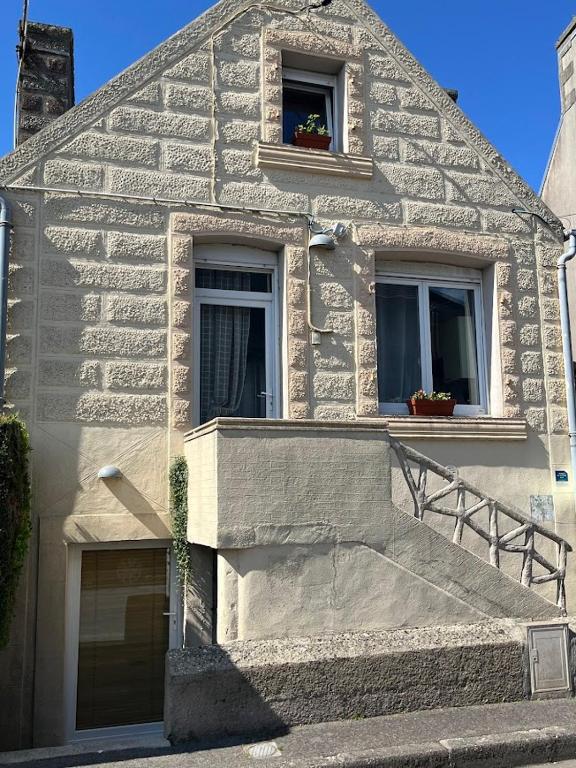 a stone house with two windows and a staircase at le gîte de Léon in Saint-Pol-de-Léon