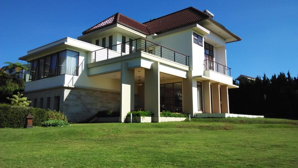 a large house with a green lawn in front of it at Villa Sophia Cimacan Puncak in Puncak