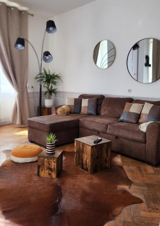 a living room with a brown couch and two wooden tables at Logement atypique en souplex in Sélestat